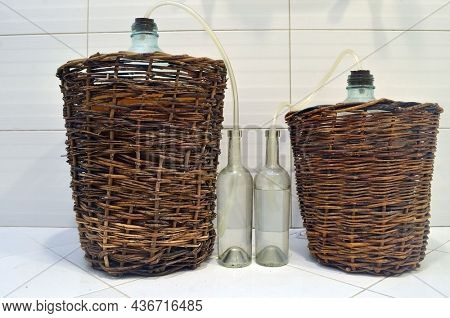 The process of making homemade wine. A glass bottles with a must with an airlock in a cork and a wine. Fermentation process.October 17, 2021. Kiev Region, Ukraine