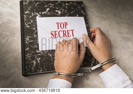 Hands Of A Man In Handcuffs On A Folder With Top Secret Information, The Concept Of Punishment For D