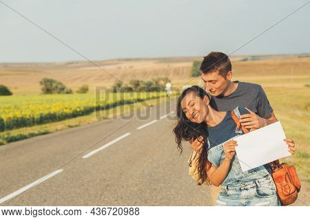 Lovers Guy And Girl Go Hitchhiking. In Hands Of Sheet With Inscription. Concept Adventures, Honeymoo