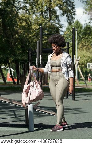 Young sportswoman putting her bag on sports facilities while going to have training