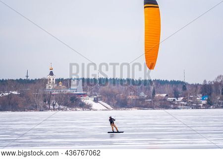 Kite Surfer Ride On Snowboard. Snowkiting In The Snow On Frozen Lake.
