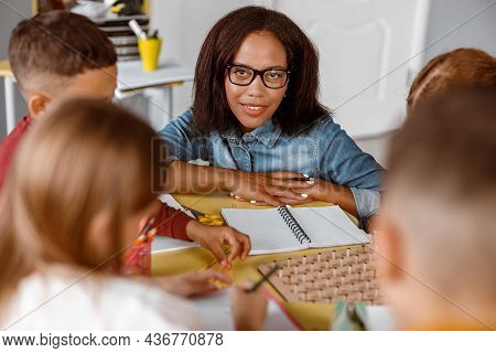Smiling Teacher Looking At Schoolchildren During Lesson