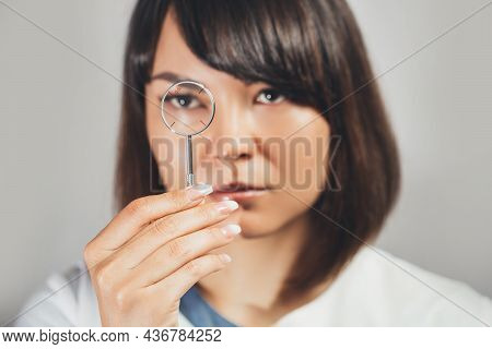 Doctor Ophthalmologist Holding Lenses To Check Patient's Vision. Focus On Lens, Face Is In Soft Focu