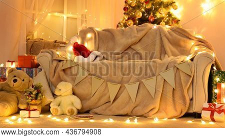 Festive Home interior - wew year or christmas decoration. At night, the room glows with festive lights. A lots of gifts and decorations. Winter holiday concept
