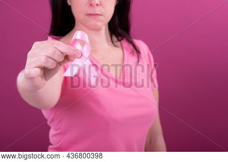 Midsection of caucasian woman in pink tshirt holding pink ribbon. breast cancer positive awareness campaign concept digitally generated video.