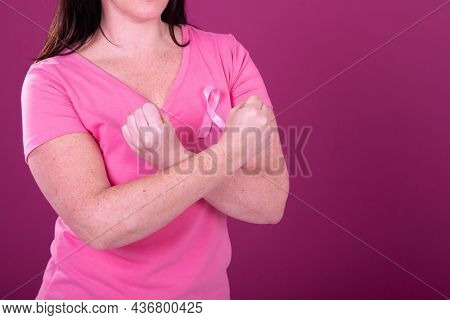 Midsection of caucasian woman in pink tshirt with pink ribbon and crossed hands. breast cancer positive awareness campaign concept digitally generated video.