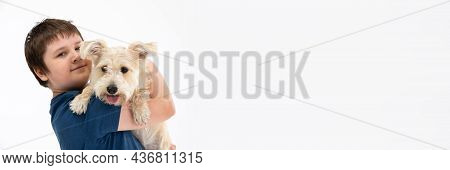 Young Boy Holds His Dog In His Arms. Subject Isolated From The Background. Panoramic Frame.