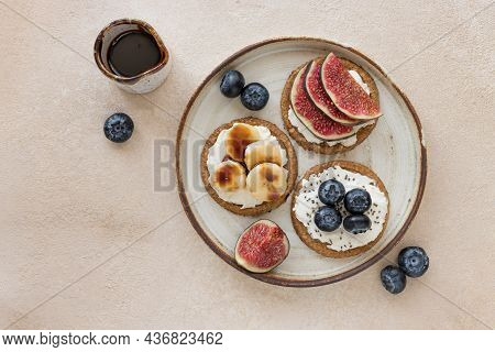 Oat Crispbread With Cream Cheese, Different Toppings And Date Syrup On Ceramic Plate. Healthy Breakf