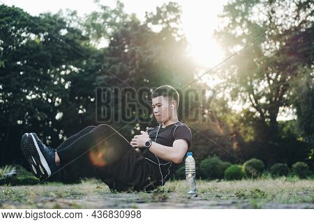 Strong Confident Young Male In Blaclk Sportswear Doing V-ups Abs Exercises Outdoor.