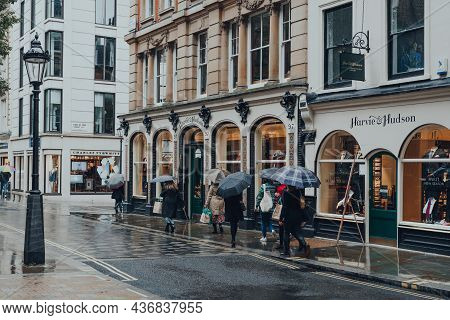 London, Uk - October 02, 2021: Women Holding Umbrellas Walk Past Harvie And Hudson, A Mens Shop Sell