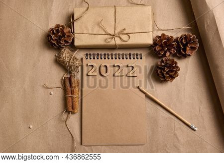 Flat Lay Arranged Composition Of A Christmas Gift In Craft Wrapping Paper, Pine Cones, Cinnamons, Ro