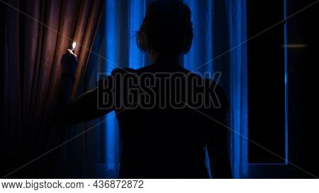 A Young Excited Woman In A Panic Runs Away From Her Pursuer Along A Dark Corridor. A Flickering Sign