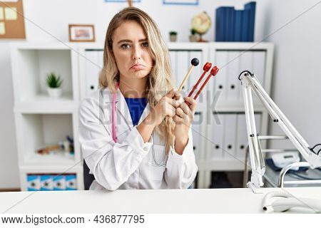 Young beautiful doctor woman holding diapason instrument depressed and worry for distress, crying angry and afraid. sad expression. 
