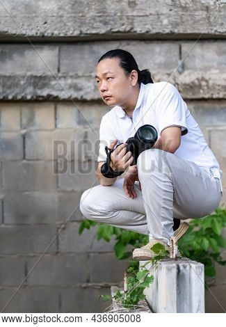 Asian Professional Cameraman Sits And Thinks About How To Create A Creativity Photo In The Construct