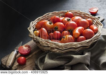 Fresh Red Tomatoes In Whicker Basket On Black Background.