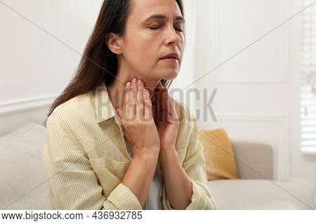 Mature Woman Doing Thyroid Self Examination At Home