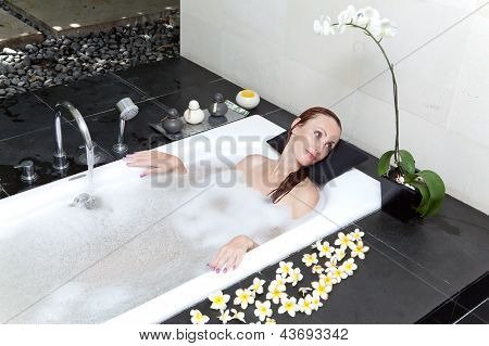ผู้หญิงวางใน soapsuds ในการอาบน้ำที่เต็ม