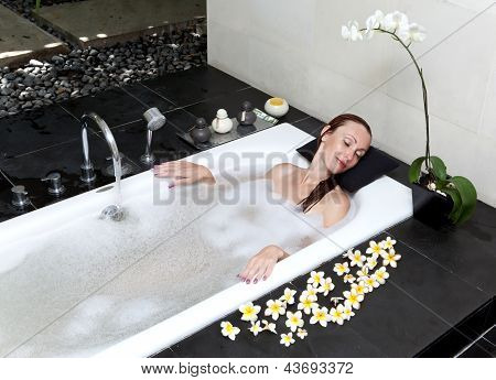 ผู้หญิงวางใน soapsuds ในการอาบน้ำที่เต็ม