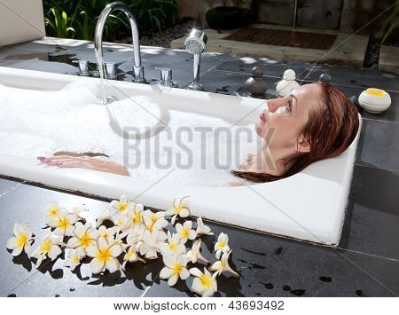 ผู้หญิงวางใน soapsuds ในการอาบน้ำที่เต็ม
