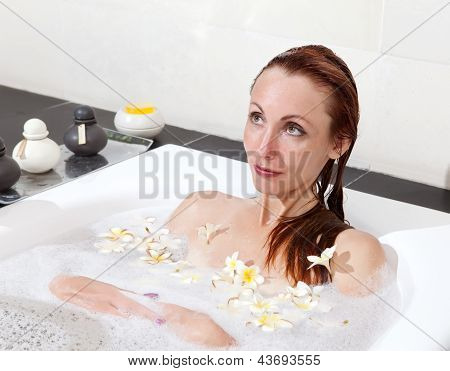 ผู้หญิงวางใน soapsuds ในการอาบน้ำที่เต็ม