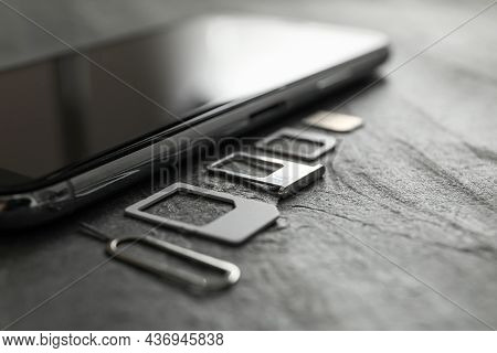 Sim Card, Mobile Phone And Ejector Tool On Grey Table, Closeup