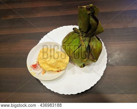 Closeup Image Of Kerala Style Tasty Biryani Wrapped In Banana Leaf And Pappadam In Plate. Selective 