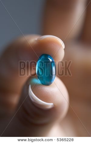 Les doigts féminins montrant une capsule bleue en gros plan
