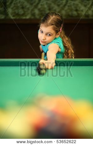 Girl teenager begins the game of billiards in the billiard hall