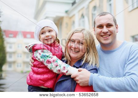 Happy mother, father and daughter walking on the street on a cloudy day