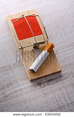 Mousetrap with cigarette, on wooden background