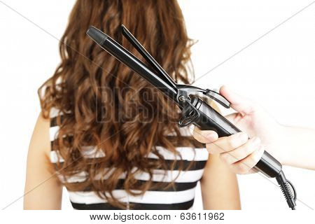 Stylist using curling iron for hair curls, close-up, isolated on white