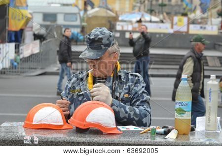 KIEV, UKRAINE - APR 19, 2014: Artist painting working helmets for tourists in the rioters camp. Putsch of Junta in Kiev. Kiev.April 19, 2014 Kiev, Ukraine 