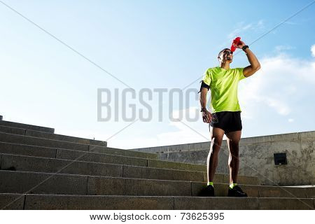 Athletic build runner resting drink energy drink after run