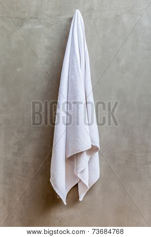 Hanging White Towel Draped On Exposed Concrete Wall In The Bathroom