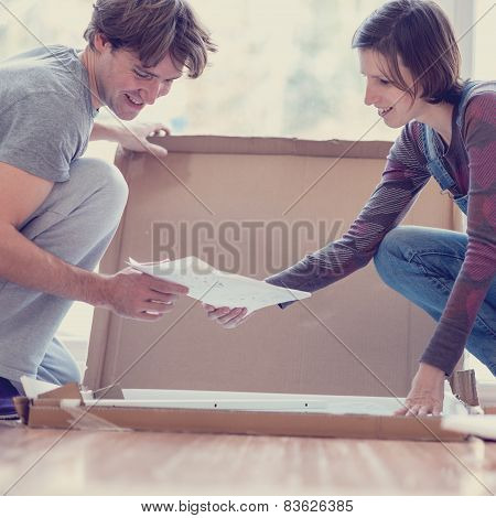 Young Couple Looking At Manual Of Self Assembly Furniture