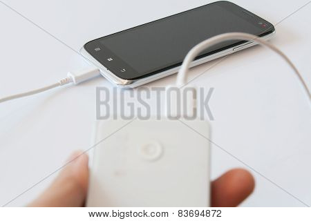 Male Hand Is Holding Power Bank Is Charging Smartphone