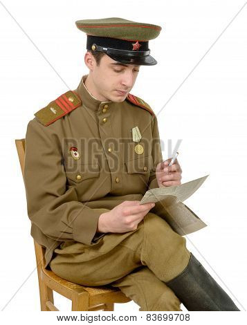 A Young Soviet Officer Sitting In A Chair Read A Newpaper
