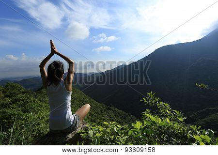 young fitness woman practice yoga at mountain peak rock