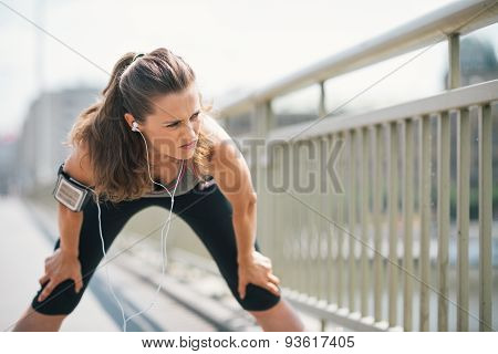 Woman Jogger Stretching On Bridge While Listening To Music