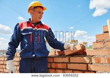 construction worker. mason bricklayer installing red brick with trowel putty knife outdoors