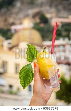 Girl's hand holding a glass with lemon ice cream.