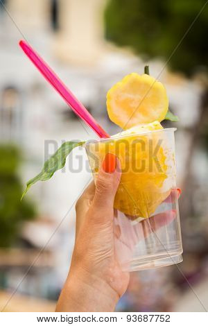Girl's hand holding a glass with lemon ice cream.
