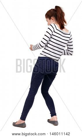 back view of standing girl pulling a rope from the top or cling to something. girl watching. Girl in a striped sweater pulls the rope side.