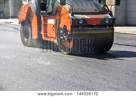Roller compactor working on the new road construction site