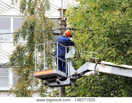 Electrical worker repairing the wires on the pole with the help of the lift car