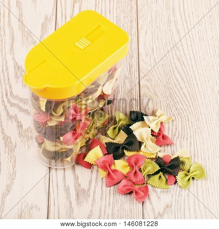 raw bow-knot pasta of different color in plastic container