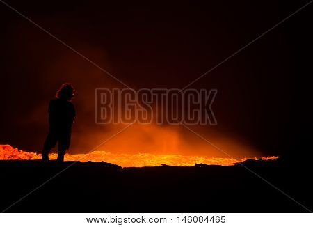 Person standing at the edge of Erta Ale active volcano in Afar Region in Ethiopia Africa at night.
