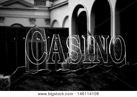 A transparent Casino sign made of glass on a rock decoration.