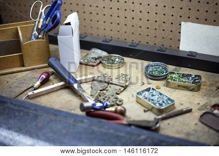 Various tools and tarnished copper buttons at a bookbinders workstation.
