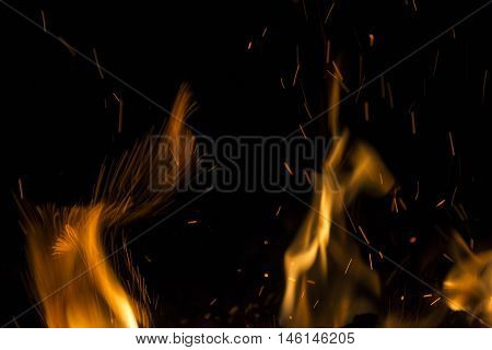 Burning fire with fiery orange flames sparks and embers exploding into the air on a dark background with copy space